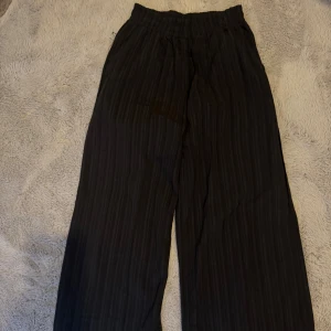 Byxor - Svarta randiga byxor med vida ben. Snygga och bekväma. Strl går att variera, stretch i midjan 