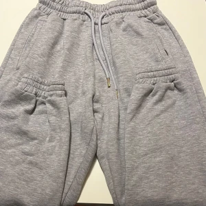 Grå mjukisbyxor från FSBN - Säljer ett par grå mjukisbyxor från FSBN i storlek XS. Byxorna har elastisk midja med snörning och praktiska fickor både fram och bak. Perfekta för en avslappnad stil. Det är också perfekt för gymmet.