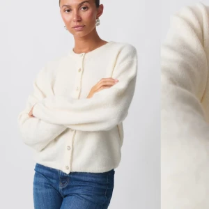 Vit kofta med knappar - Mysig vit kofta med knappar framtill. Den har en rund halsringning och långa ärmar, perfekt för kyligare dagar. Koftan är i ett mjukt material som ger en skön känsla. Använd bara nån enstaka gång. 