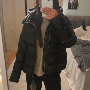 Svart pufferjacka från Colmar - Säljer en svart pufferjacka från Colmar. Jackan har en hög krage och dragkedja framtill. Perfekt för kyliga dagar med sin vadderade design. Helt ny med prislappen kvar!