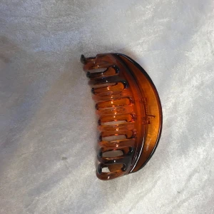 Snygg hårklämma - Snygg brun hårklämma i plast med en klassisk design. Perfekt för att hålla håret på plats med stil. Den har en glansig yta och en robust konstruktion. Finns fler kvar, samma frakt  , helt ny 