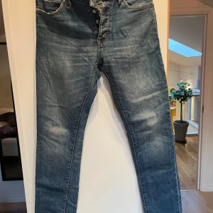 Blå jeans från Neuw - Säljer ett par snygga blå jeans från Neuw i modellen Lou Slim. De har en klassisk femficksdesign och knappgylf. Perfekta för en stilren look.