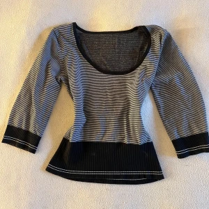 Randig topp med trekvartsärm - Snygg randig topp med trekvartsärm och rund halsringning. Svart och vit design med kontrasterande breda ränder vid ärmslut och nederkant. 