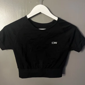 Svart kortärmad topp från ICIW - Säljer en snygg svart kortärmad topp från ICANIWILL. Toppen har en tight passform och är croppad. Perfekt för träning eller en sportig look. Har använt ett fåtal gånger💗
