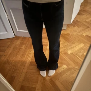 Mörkblåa boot cut jeans  - Snygga mörkblåa bootcut jeans med klassisk femficksdesign. Perfekta för en stilren look. De har en bekväm passform och är tillverkade i ett slitstarkt material.