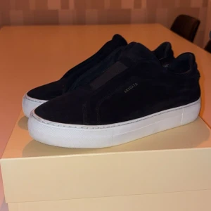 Svarta sneakers från Axel Arigato - Snygga svarta sneakers från Axel Arigato i mocka med vit sula. . Skorna har en minimalistisk design utan snörning. Skick 8/10  storlek 40 priset är inte hugget i sten 