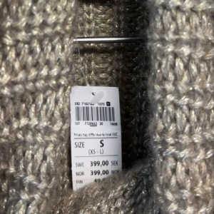 Beige stickad polotröja - Mysig beige stickad polotröja med en avslappnad passform. Perfekt för kyliga dagar med sin varma och bekväma design. Tröjan har långa ärmar och en stor polokrage som ger extra värme och stil.