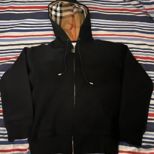 Svart burberry zip hoodie - Varan säljs pga ingen användning alls. Ganska liten för mig och passar inte min stil direkt. Helt ny köpt och i perfekt skick. Vid frågor eller intresse så är de bara att skriva!