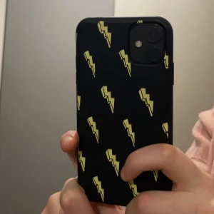 Svart mobilskal med blixtmönster - Snyggt svart mobilskal med ett coolt blixtmönster i gult. Perfekt för att ge din telefon en unik look och extra skydd. 
