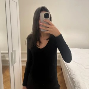 Svart långärmad topp - Säljer en stilren svart långärmad topp. Perfekt för både vardag och speciella tillfällen. Toppen har en enkel design med en rund halsringning.