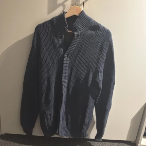 Mörkblå stickad kofta  - Säljer en snygg mörkblå stickad kofta med knappar och hög krage. Perfekt för kyliga dagar för den är tjock och varm. Storlek L