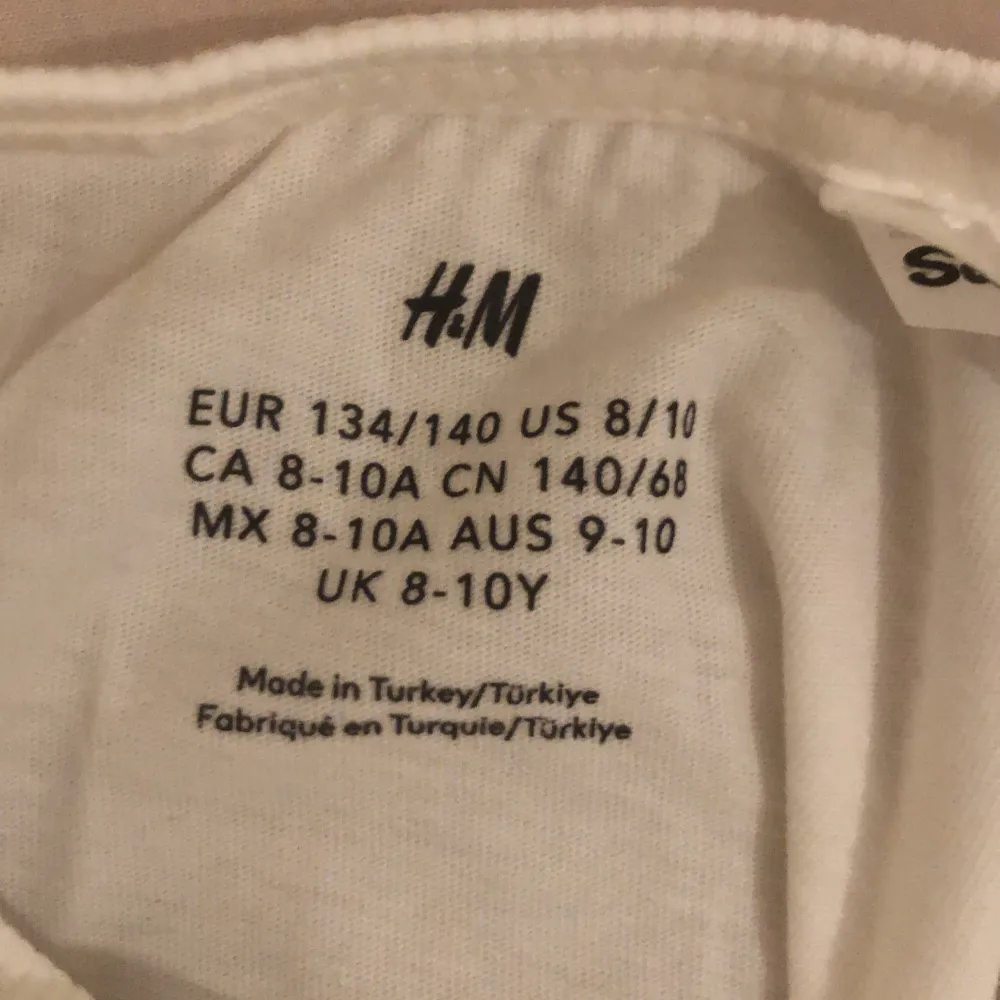 Söt vit t-shirt från H&M med ett stort Hello Kitty-tryck i silver och rosa. Perfekt för alla Hello Kitty-fans! T-shirten har korta ärmar och är gjord i mjukt bomullsmaterial.. T-paidat.