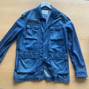 Blå jeansjacka/overshirt från Dondup - Snygg blå jeansjacka från Dondup med flera praktiska fickor framtill. Jackan har en klassisk krage och långa ärmar, perfekt för en avslappnad stil. Den är tillverkad i ett slitstarkt denimtyg och har en stilren design.