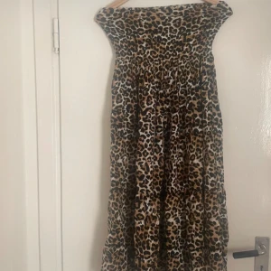 Leopardmönstrad klänning från Amelie & Me - Trendig leopardmönstrad klänning från Amelie & Me. Klänningen har en offshoulder-design och är perfekt för att sticka ut. Den är i en bekväm passform och har en luftig känsla.