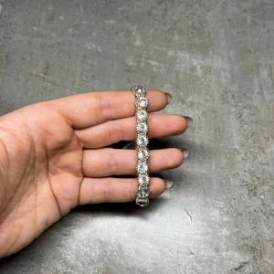 Glittrigt armband från Tomato - Snyggt glittrigt armband från Tomato i silverfärg. Armbandet är dekorerat med stora, gnistrande stenar som ger en lyxig känsla. Perfekt för att lägga till lite extra glamour till din outfit.