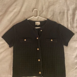 Svart kortärmad kofta från H&M - Säljer en superfin svart kortärmad tröja från H&M. Gulddetaljer. Pris kan diskuteras 💕