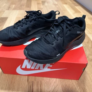 Svarta Nike sneakers - Snygga svarta Nike sneakers med snörning. Perfekta för en sportig look och bekväma för vardagsbruk. Stilren design med diskret Nike-logga på sidan.