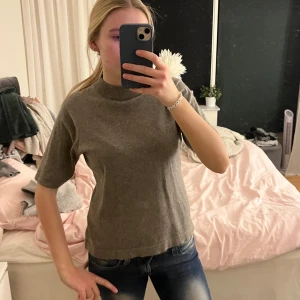 Grå stickad tröja - Säljer en stilren grå stickad tröja med korta ärmar och hög krage. Perfekt för en avslappnad look. Skriv om ni har några frågor!💞