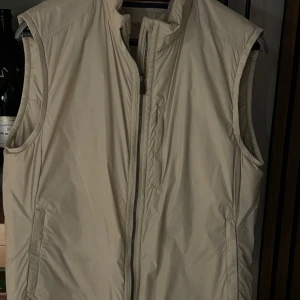 Väst - Oandvänd Snoot väst i storleken M. Nypris 2000 kr, mitt pris 900 kr. Säljer en stilren beige väst med dragkedja. Västen är i nytt skick då den alldrig andvänds men taggar fin ej.