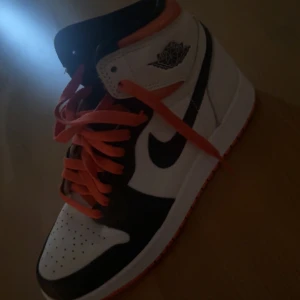 Nike Air Jordans med orange snörning - Snygga Nike Air Jordans i svart och vitt med en orange snörning. Perfekta för att ge din outfit en sportig touch. Köpte skorna för 3000kr. 