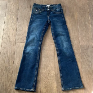 Blå jeans med bootcut - Snygga blå jeans med bootcut-stil och klassisk femficksdesign. Perfekta för en avslappnad look. De har en knapp och dragkedja framtill.