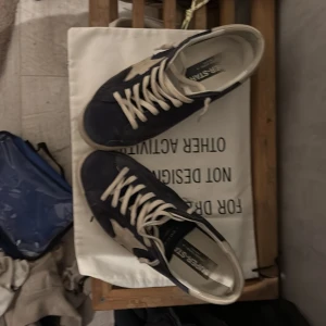 Blå sneakers från Golden Goose - Snygga blå sneakers från Golden Goose med vita stjärndetaljer och snörning. Tillverkade i Italien, dessa skor kombinerar stil och komfort perfekt. Perfekta för en avslappnad look.