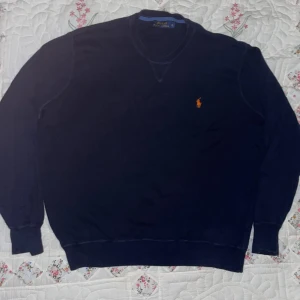 Mörkblå tröja från Ralph Lauren - Säljer en klassisk mörkblå tröja från Ralph Lauren med det ikoniska broderade logotypen i orange på bröstet. Tröjan har långa ärmar och en rund halsringning. Perfekt för en stilren look. Och är i PERFEKT skick!! Pris kan diskuteras 