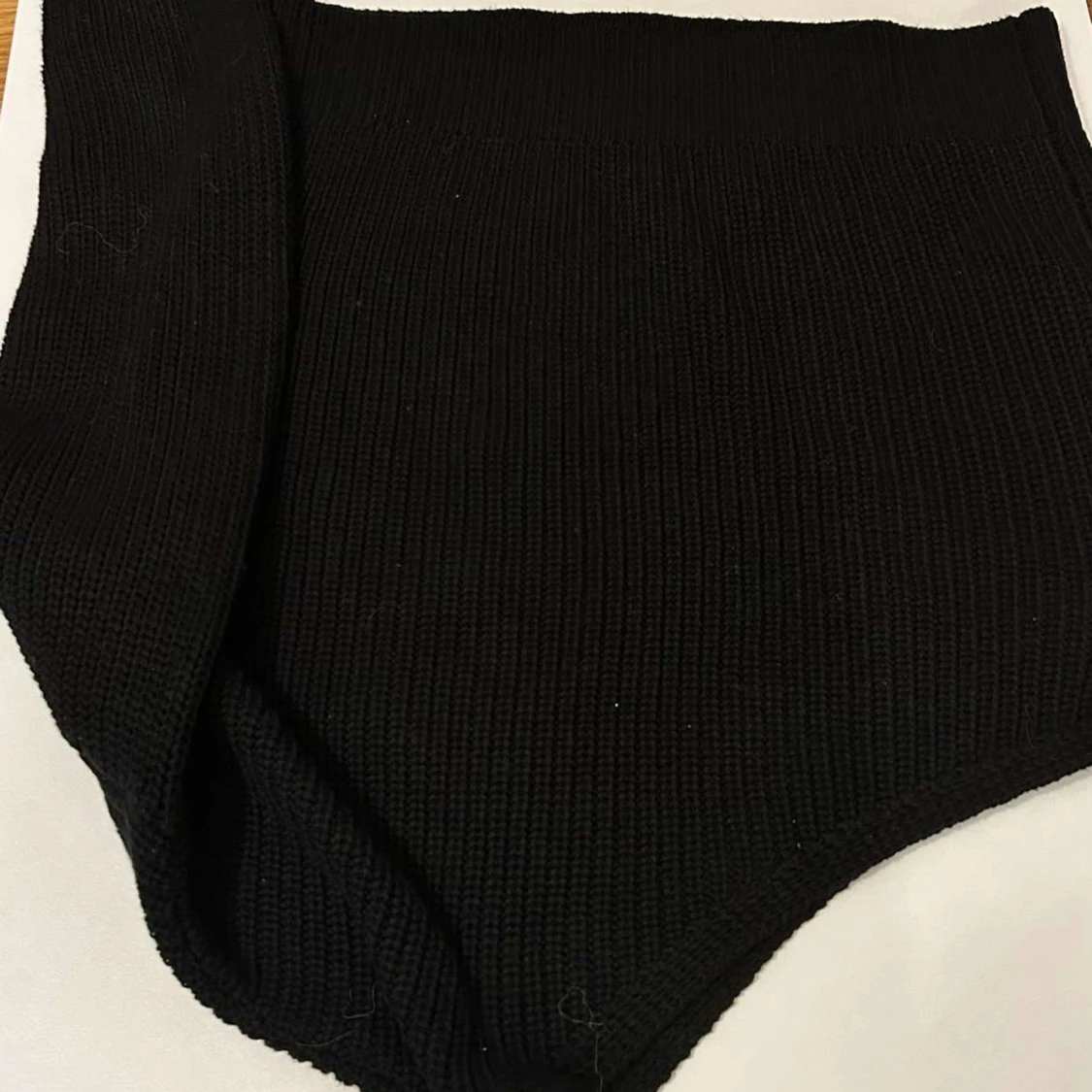 Svart stickad med en arm