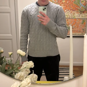 Grå kabelstickad tröja från Ralph Lauren - Säljer en stilren grå kabelstickad tröja från Ralph Lauren. Tröjan har en klassisk design med rund hals och det ikoniska broderade logotypen på bröstet. Perfekt för kyligare dagar och ger en tidlös look. Skick 10/10 använd 2-3 gånger. Storlek XL på junior 18-20år men sitter som mellan s och m