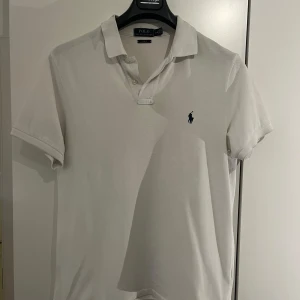 Vit pikétröja från Ralph Lauren - Säljer en stilren vit pikétröja från Ralph Lauren i slim fit storlek L, Perfekt för en avslappnad men ändå elegant look, super bra skick! Mitt pris: 329kr, bara att höra av sig vid ytterligare funderingar!😁