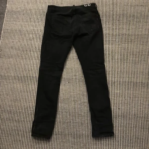 Svarta skinny jeans från dundop - Snygga svarta skinny jeans från George Dundop i storlek 32. De har en modern passform med slitna detaljer.