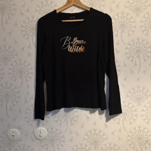 Svart långärmad topp från Vero Moda - Snygg svart långärmad topp från Vero Moda med textdetalj i vitt och orange på framsidan. Perfekt för en avslappnad stil. Tillverkad i ett mjukt och bekvämt material.