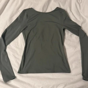 Khaki långärmad backless topp från Weekday - Snygg khaki långärmad och backless topp från Weekday. Perfekt för en stilren look. Tillverkad i Turkiet.