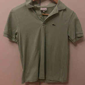 Grön pikétröja från Lacoste - Snygg grön pikétröja från Lacoste passar runt 164cm.