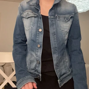 Blå jeansjacka från Replay - Snygg blå jeansjacka från Replay med klassisk design och knappar framtill. Jackan har två bröstfickor och långa ärmar. Perfekt för en avslappnad stil. Står storlek L men skulle säga att den passar S/M bättre. 