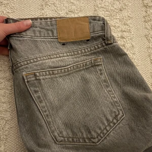 Grå jeans från weekday - Snygga grå jeansbyxor med klassisk femficksdesign och knappgylf. Perfekta för en avslappnad stil. De har en rak passform som ger en tidlös look.modellen är arrow,stl: 24/32