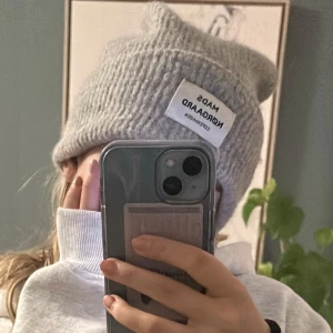 Grå stickad mössa från Mads Nørgaard - Snygg grå stickad mössa från Mads Nørgaard med en uppvikt kant och en vit etikett framtill. Nästintill oanvänd!