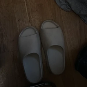 Yeezy slides. - Yeezy slides i färgen beige. Köptes nya för 2000kr. Box följer med. Storlek 45-46. Lite fläckar här och där därav priset.