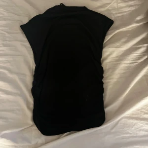 Svart ärmlös topp - Snygg svart ärmlös topp i mjukt material. Perfekt för en stilren look. Passar bra till både jeans och kjol.