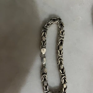 Silverfärgat armband - Snyggt och robust silverfärgat armband med en kedjedesign. Perfekt för att ge en stilren touch till din outfit. Armbandet har en säker låsning och en klassisk look. Pris kan diskuteras! Den är väldigt tjock i bredden och är 24 centimeter lång. 