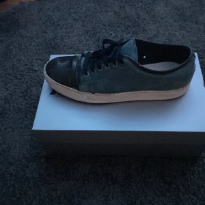 Blå Lanvin sneakers med svarta detaljer öppen för bud!!! Över 1000kr - Snygga blå sneakers med svarta snörningar och tåparti. Skorna har en vit sula som ger en fräsch kontrast. Perfekta för en avslappnad stil.