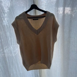 Beige stickad väst från Gina Tricot - Säljer en superfin beige stickad väst från Gina Tricot. Den har en snygg v-ringning och är perfekt för lager-på-lager-stil. Västen är i ett mjukt och bekvämt material, perfekt för höst och vår. Passar både till vardags och lite mer uppklädda tillfällen.