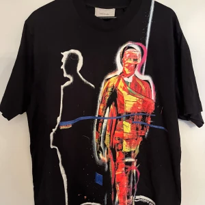 Svart t-shirt med konstnärligt tryck - Säljer en svart t-shirt från Limitato med ett coolt konstnärligt tryck på framsidan. Trycket föreställer en färgglad figur i rött, orange och blått, vilket ger en unik och kreativ look. Perfekt för dig som vill sticka ut!