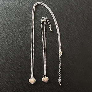Matchande Halsband och Armband - Ett matchande oanvänt silvrigt halsband och armband med ett hjärta. Osäkee på vilket material dom är gjorda i. Katt och hund finns i hemmet!  