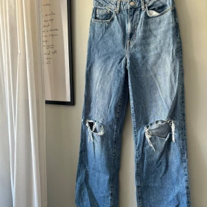 Blå jeans med slitningar - Säljer ett par snygga blå jeans från lager 157 med  slitningar på knäna. Midjemått: ca 72cm Längd: ca 109cm Benöppning: ca 24cm. 