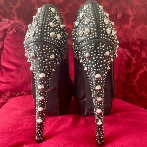 Högklackade skor med nitar - Ej använda. Dock lite märken på skorna och skinnimmitation som börjat skavas bort vid hälen. Undersidan helt opåverkad då de bara testats. Märkena är efter att de legat nerpackade bland andra skor. 