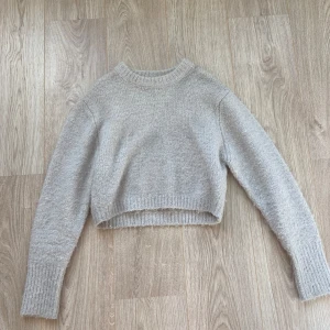 Stickad tröja - En liten croppad vit/grå stickad tröja från zara. Använd ett par gånger men är fortfarande i bra skick. Det har blivit lite svart på högra axeln som ni kan se på bilderna men annars inga fel.