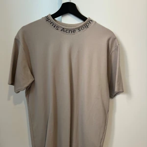Acne T-shirt  - En beige Acne t-shirt i normalpassform använd 3 gånger. Nypris ligger på 2700kr.