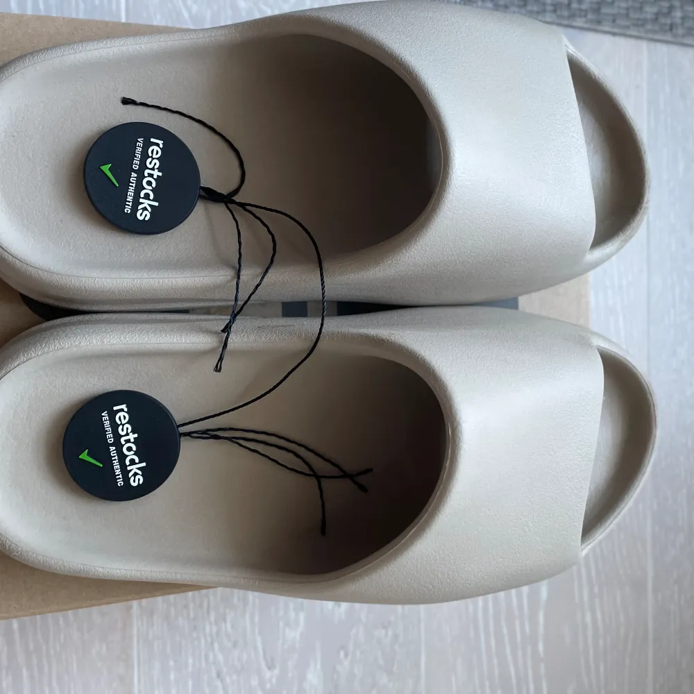 Säljer dessa Yeezy slides som är köpta på restocks hemsida. Finns en liten defekt som man kan se på bild två men syns knappt. Skulle säga att de passar storlek 42  Tveka inte på att komma med frågor🌟. Skor.