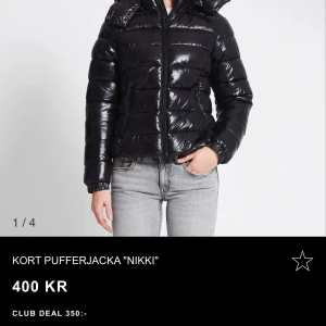 Kort pufferjacka ”Nikki” - Kort puffjacka i vävd kvalitet. Tight passform, huva och långa ärmar. Blank yta Fodrad Är lite osäker om jag ska sälja den, så skriv gärna vid intresse! Avtagbar huva 2-vägsdragkedja Resår vid ärmslut Fickor med dragkedja